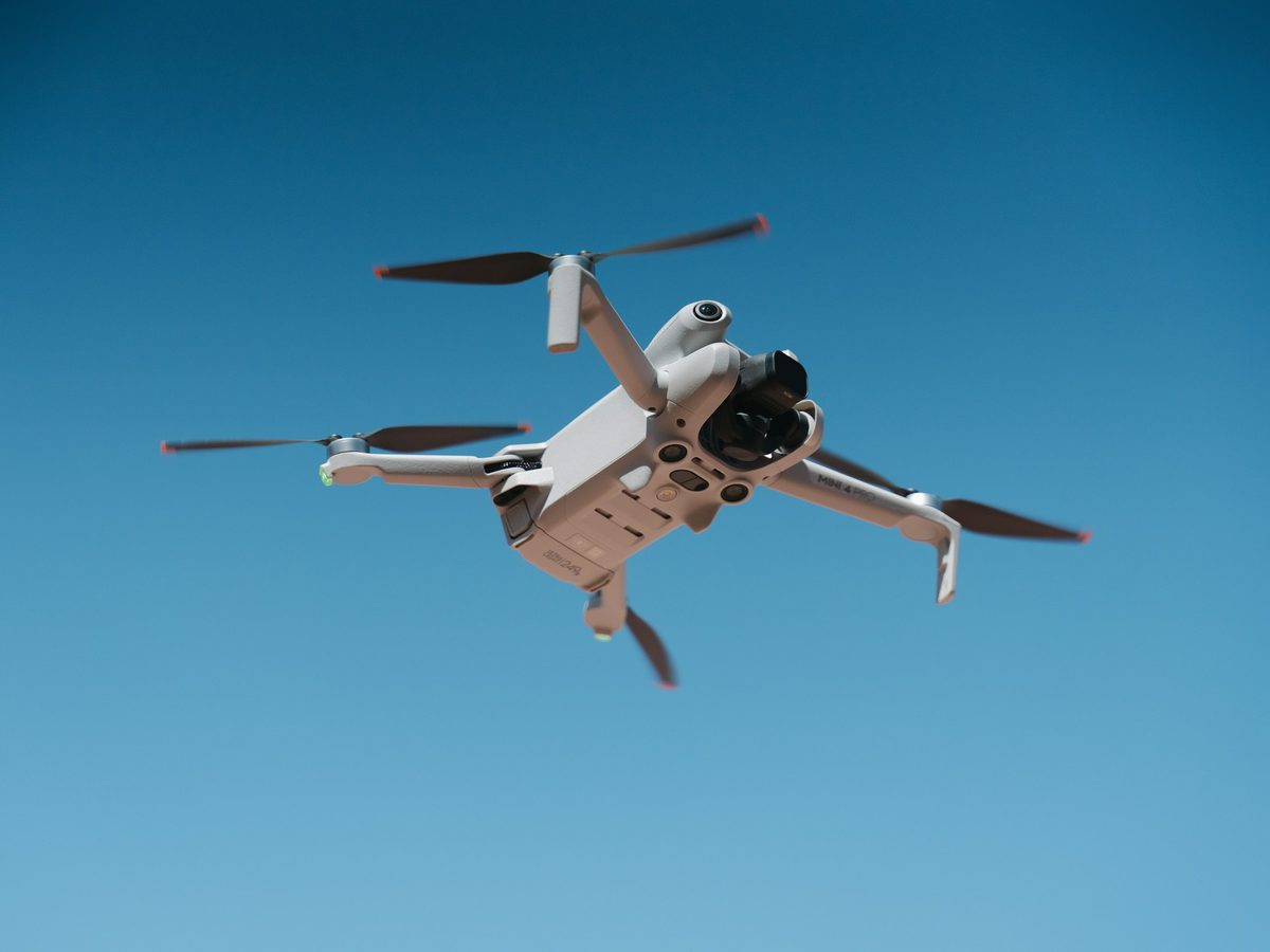 A small drone flying against a blue sky